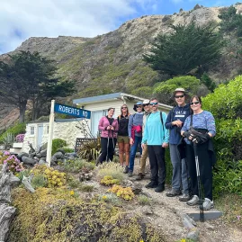 Group of hikers posing near Robert’s Road sign at Boulder Bay, Banks Peninsula