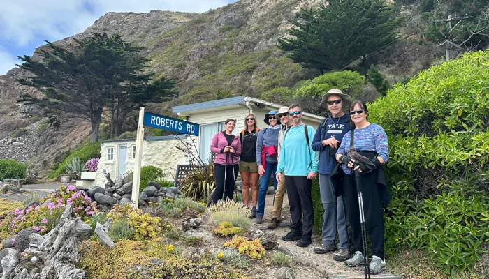 Group of hikers posing near Robert’s Road sign at Boulder Bay, Banks Peninsula