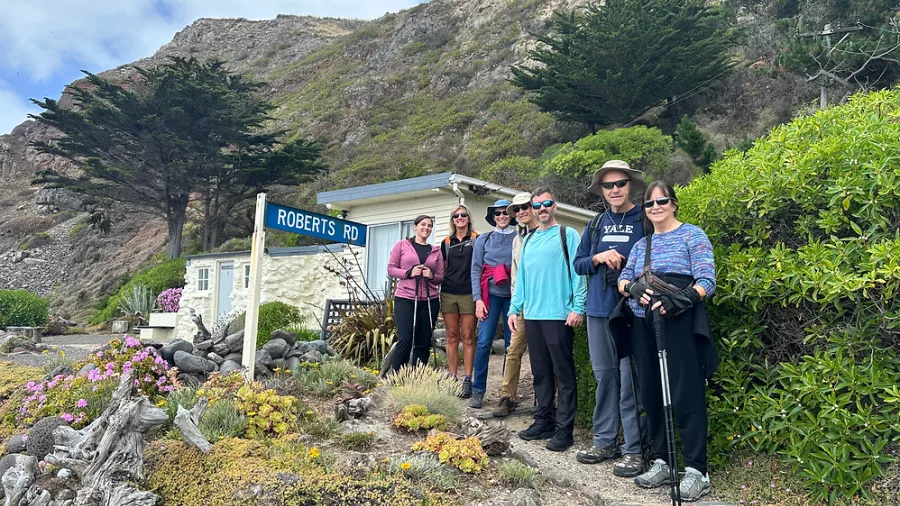 Group of hikers posing near Robert’s Road sign at Boulder Bay, Banks Peninsula