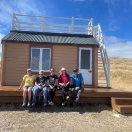 Hiking group sitting outside Scott’s Hut on the Crater Rim Walk near Godley Head