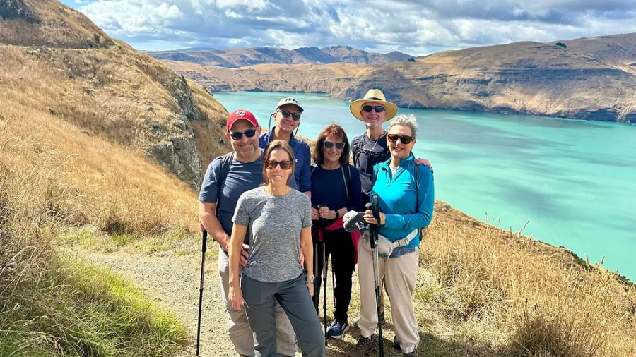 Group of six smiling hikers with stunning views of turquoise waters on the Crater Rim Walk