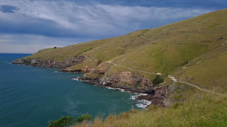 Steep coastal cliffs and a walking path curving around the hillside above the Pacific