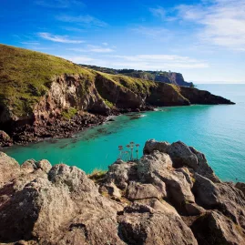 Rocky coastal cliffs and calm turquoise waters near Boulder Bay on Banks Peninsula