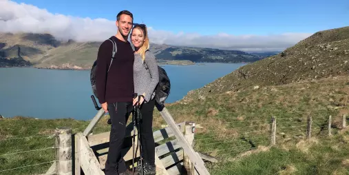 Couple posing with hiking poles on a stile above Lyttelton Harbour during a private guided walk