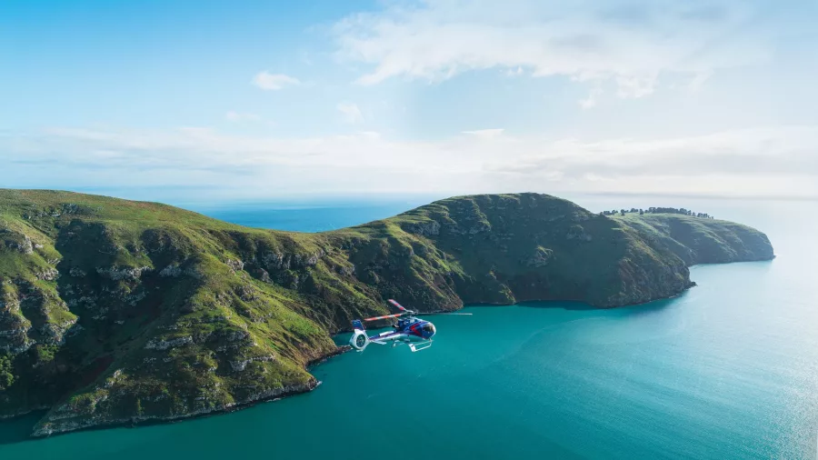 Helicopter flying over Banks Peninsula coastline on a scenic flight from Christchurch to Akaroa