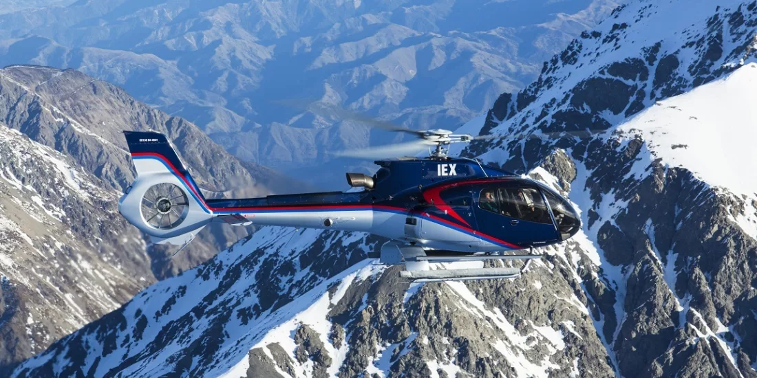 Helicopter flying above dramatic snow-covered mountain ridges in the Southern Alps