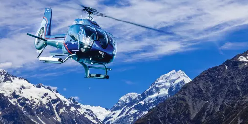 Helicopter soaring through snowy mountain peaks near Mount Cook