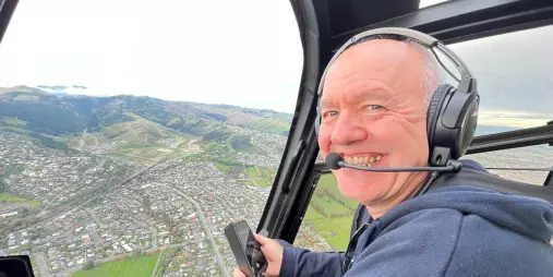 Happy helicopter passenger overlooking Christchurch cityscape
