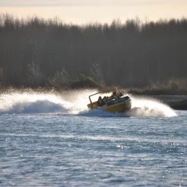 Yellow jet boat splashing water during fast turn on river