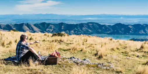 Couple enjoying a romantic picnic on Mount Herbert overlooking Lyttelton Harbour in Canterbury, New Zealand