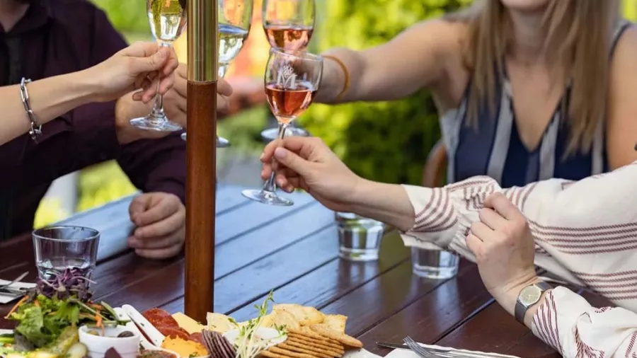 Friends toasting with glasses of white and rosé wine over a platter at Melton Estate Winery