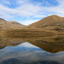 Golden mountains reflecting perfectly in a calm lake near the Edoras filming location.