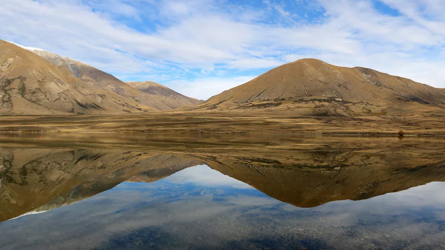 Golden mountains reflecting perfectly in a calm lake near the Edoras filming location.
