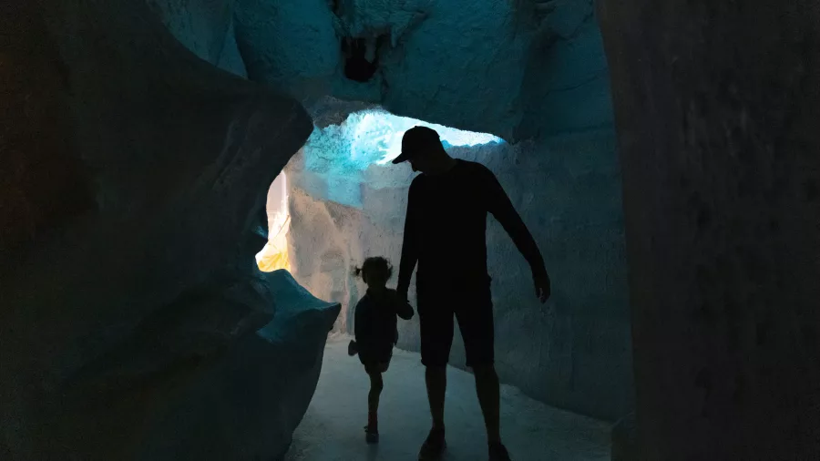 Silhouettes of a parent and child walking through the Ice Cave exhibit at the Antarctic Centre