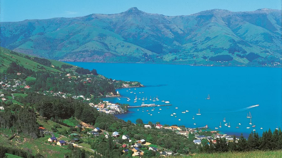 Elevated view of Akaroa township with boats in the harbour and surrounding hills