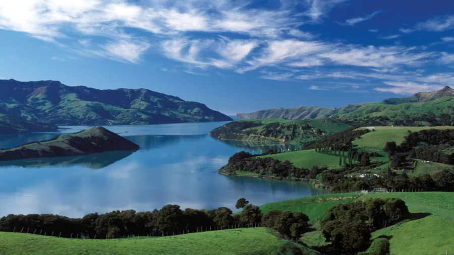 Scenic view of Akaroa Harbour with rolling green hills and blue skies