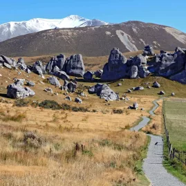 Walking track through the limestone boulders of Castle Hill with snowy peaks in the background