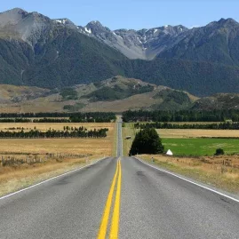 Straight road leading to Arthur’s Pass with dramatic Southern Alps mountain backdrop