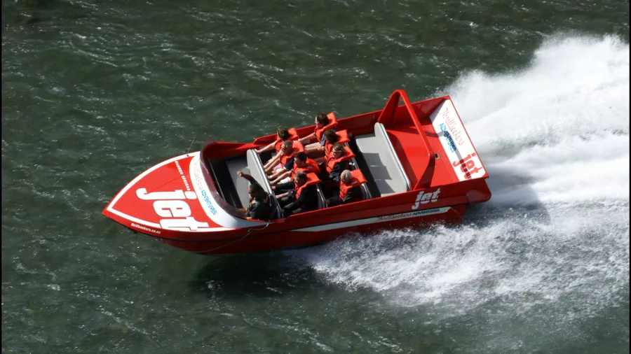 Aerial shot of red jet boat making high-speed turn on the Waiau River