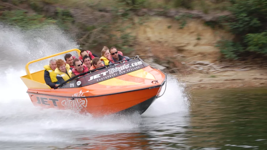 Side view of jet boat at speed with passengers enjoying the ride on the Waimakariri River