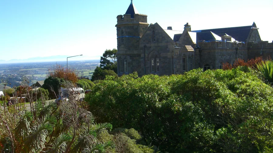 The historic Sign of the Takahe building in Christchurch, surrounded by lush greenery and blue skies.