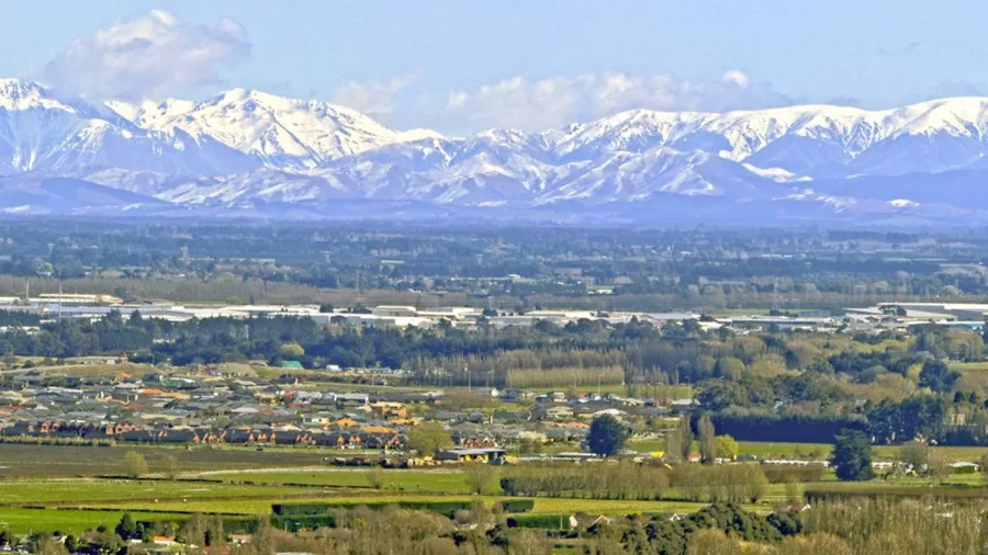 View across the lush Canterbury Plains towards the snow-capped Southern Alps, New Zealand.