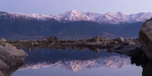 Kaikōura mountains reflected in rock pool at dusk