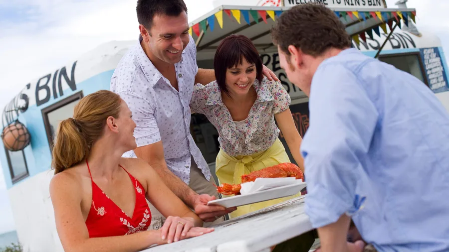 Friends sharing freshly cooked crayfish at Nin’s Bin, Kaikōura