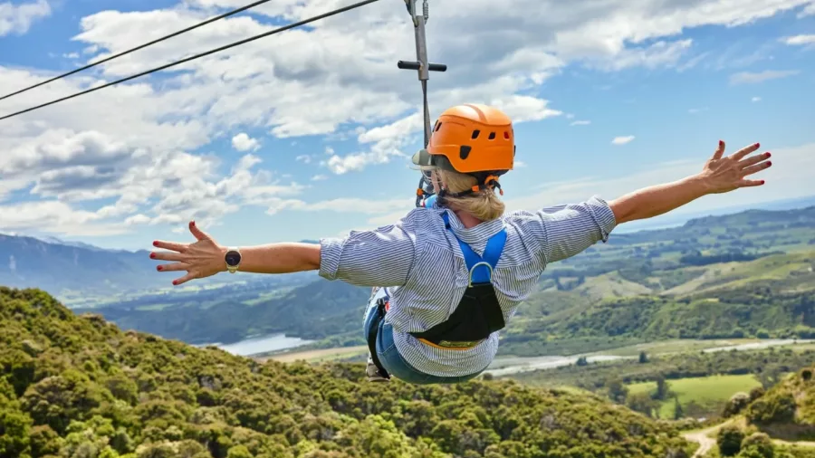 Solo zipliner rides with arms wide open above the Kaikōura countryside.