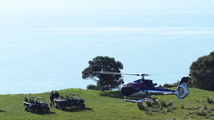 4x4 quad bike and helicopter overlooking bright blue Kaikōura coastline from a hilltop landing