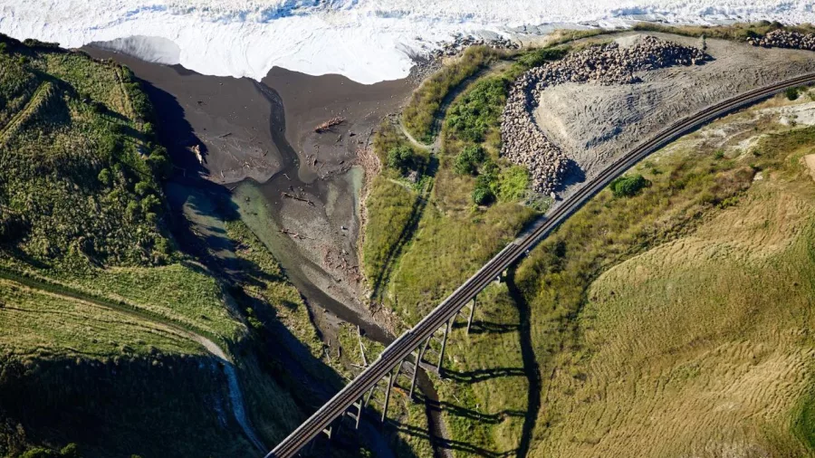 Aerial view of a bridge crossing rugged coastal terrain on the Kaikōura Grand Alpine Helicopter Tour