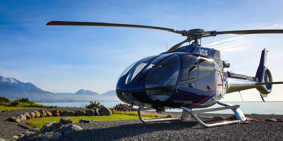 Kaikōura Helicopter parked near the coast with stunning mountain and sea backdrop