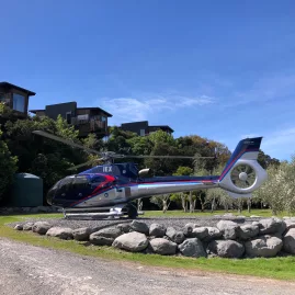 Helicopter landed outside Hapuku Lodge surrounded by native greenery