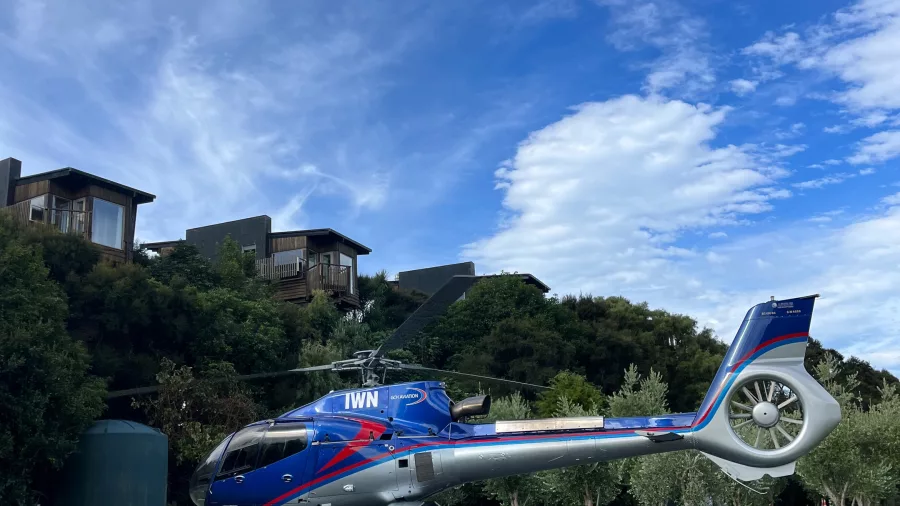 Hapuku Lodge and Kaikōura Helicopter under a bright blue sky with native garden