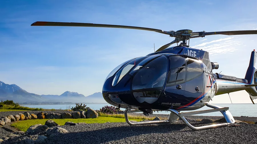 Kaikōura Helicopter parked near the coast with stunning mountain and sea backdrop
