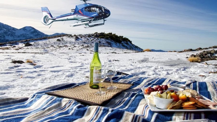 Snowy mountaintop picnic with food, wine, and helicopter overhead in Kaikōura