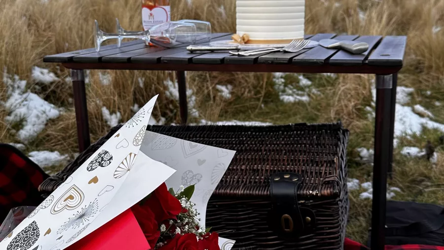 Romantic alpine picnic with flowers, wine, and a helicopter in the background near Kaikōura