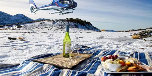 Snowy mountaintop picnic with food, wine, and helicopter overhead in Kaikōura