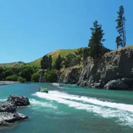 Jet boat speeding along turquoise water through the Hurunui River gorge in North Canterbury