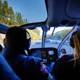 Passengers view the Hurunui River landing site from the cockpit of a Kaikōura Helicopters flight