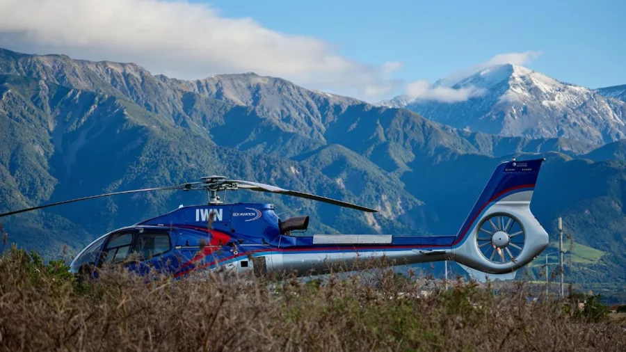 Helicopter waiting on the ground with dramatic mountain backdrops in Canterbury