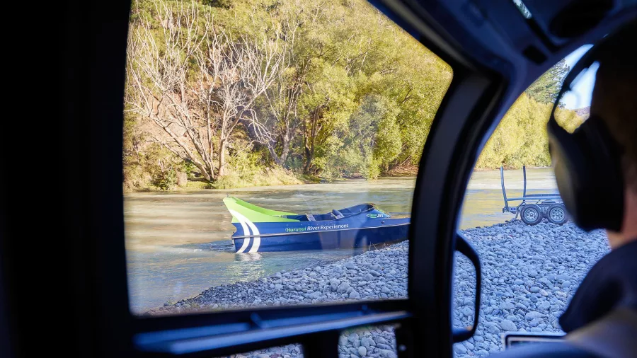 Looking through helicopter window at jet boat waiting on the river during Heli-Jet tour