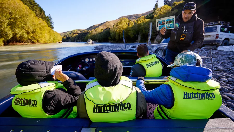 Guide giving a safety briefing to guests seated in a jet boat before departure on the Hurunui River