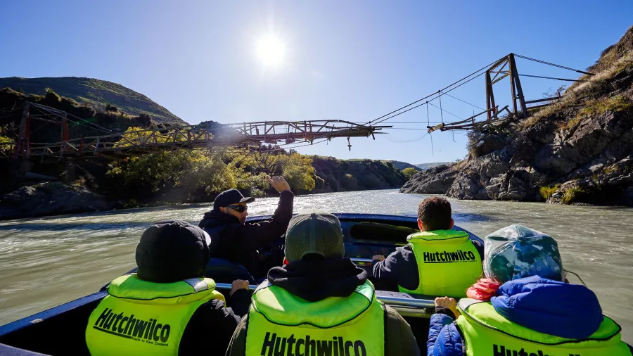 Jet boat passing under a historic bridge on the Hurunui River during Kaikōura Helicopters tour