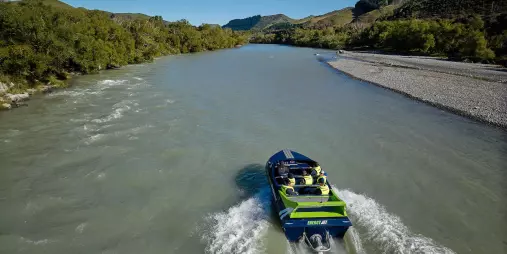 Jet boat making a wide turn on the river with passengers enjoying the view