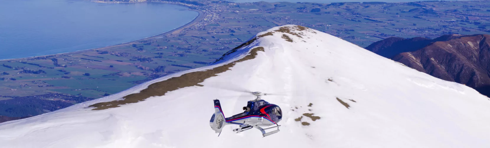 Kaikōura Helicopters flying over snow-covered summit ridge of Mt Fyffe in winter