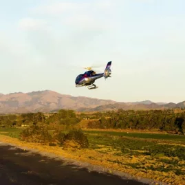 Helicopter flying over Kaikōura coastline with evening sun lighting the scene