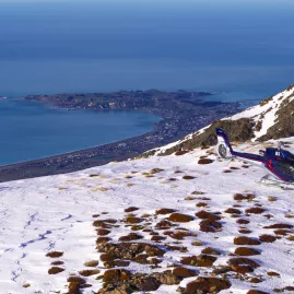 Helicopter landed in snow on Mt Fyffe with Kaikōura Peninsula and ocean in the distance