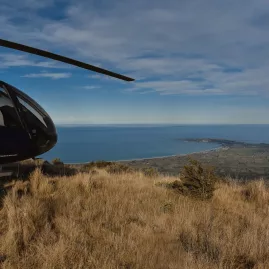 Helicopter parked on Mt Fyffe summit with ocean and Kaikōura township below