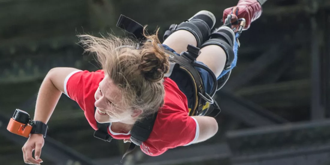Woman smiling mid-fall during a solo bungy jump in Hanmer Springs